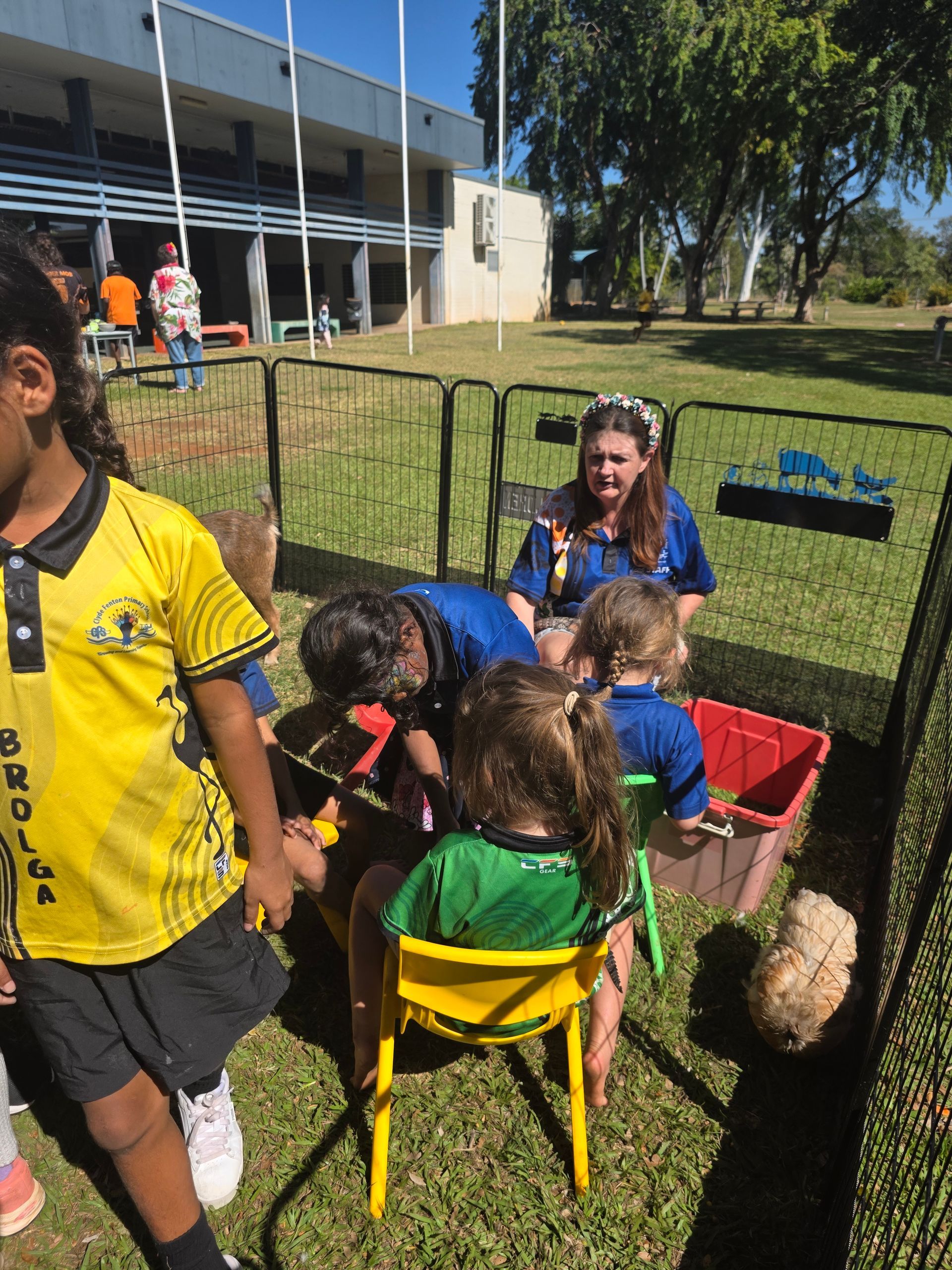 A group of children are playing in a sandbox with a woman standing behind them.