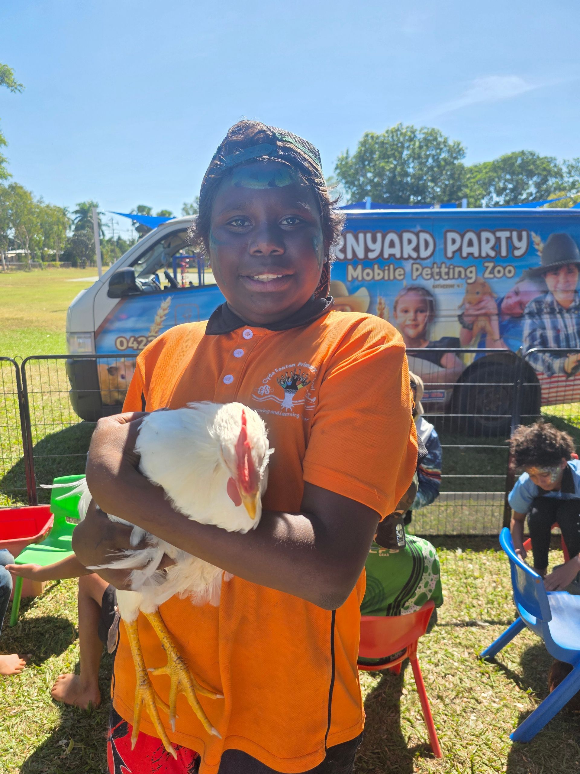 A young boy is holding a white chicken in his arms.
