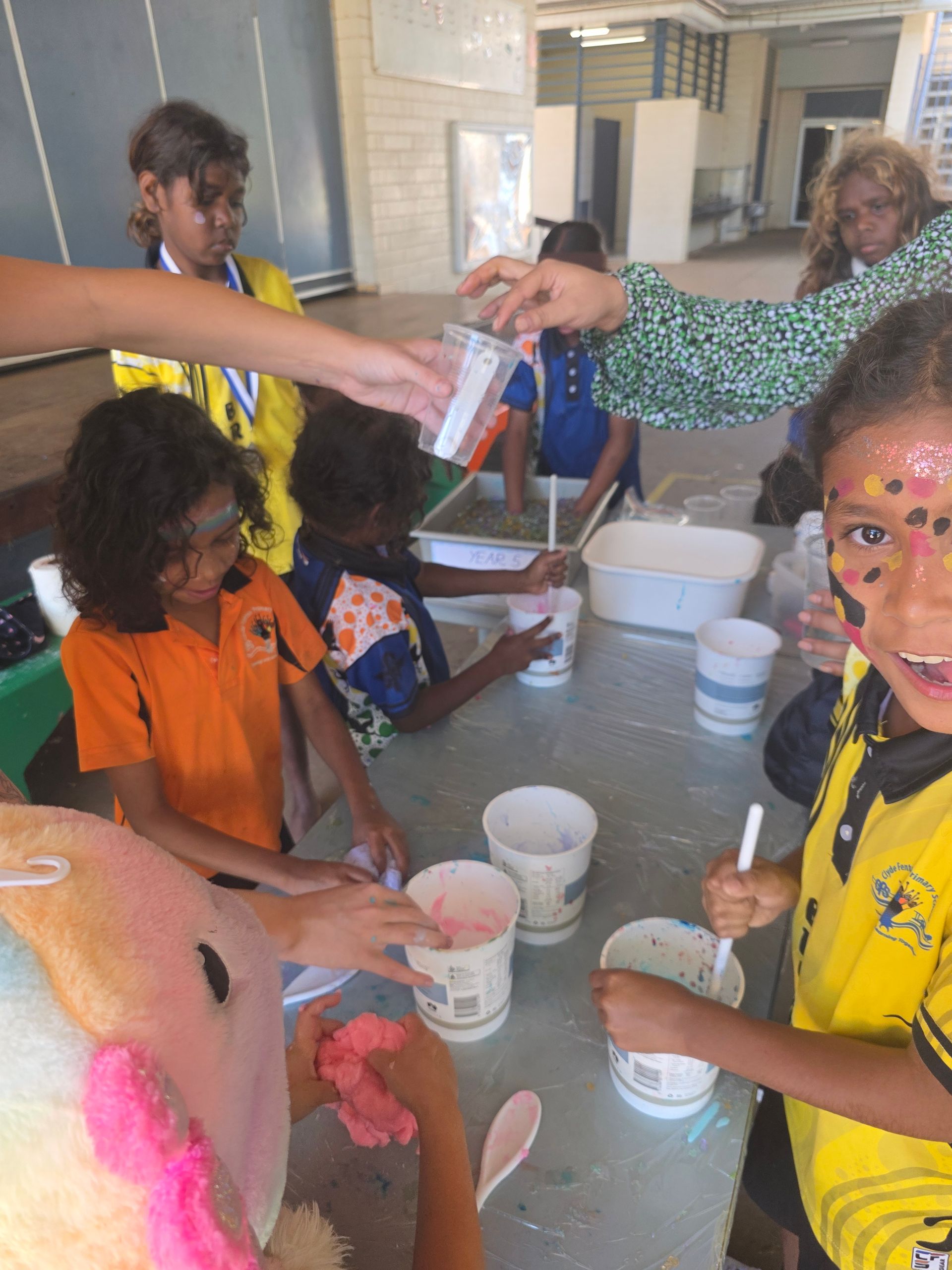 A group of children are sitting around a table with cups and spoons.