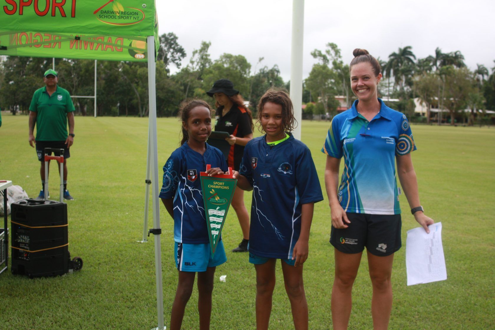 A group of people standing in a field under a sign that says sport