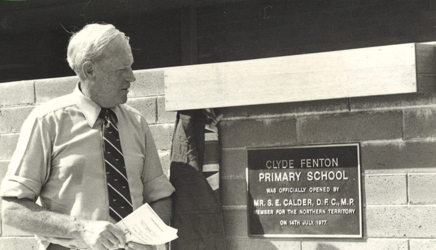 A man standing in front of a sign that says clyde fenton primary school