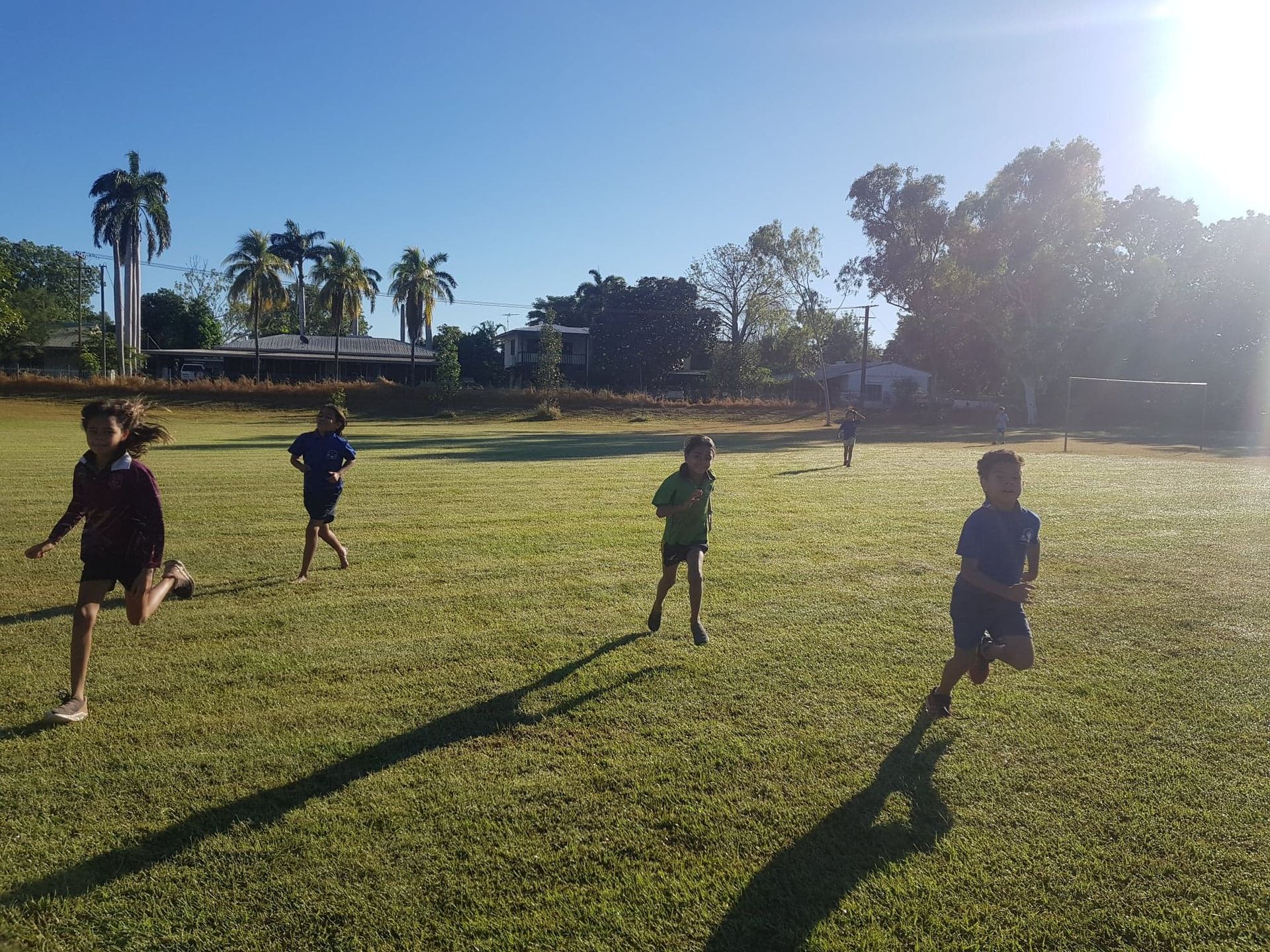 A group of children are running on a grassy field.