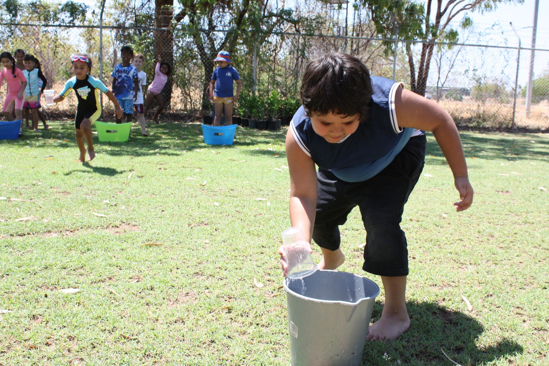 A young boy is pouring water into a bucket