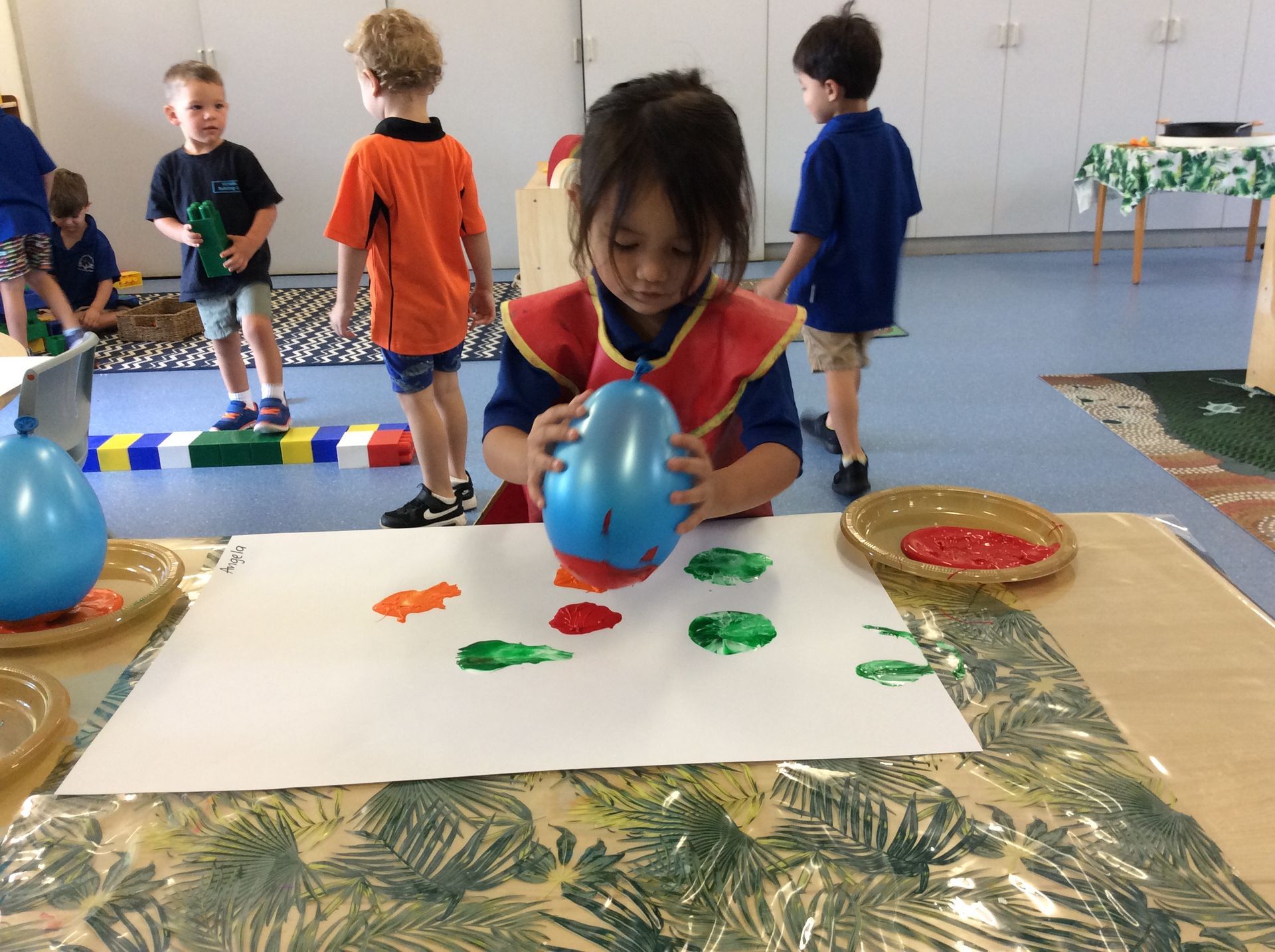 A little girl is playing with a blue balloon on a table.