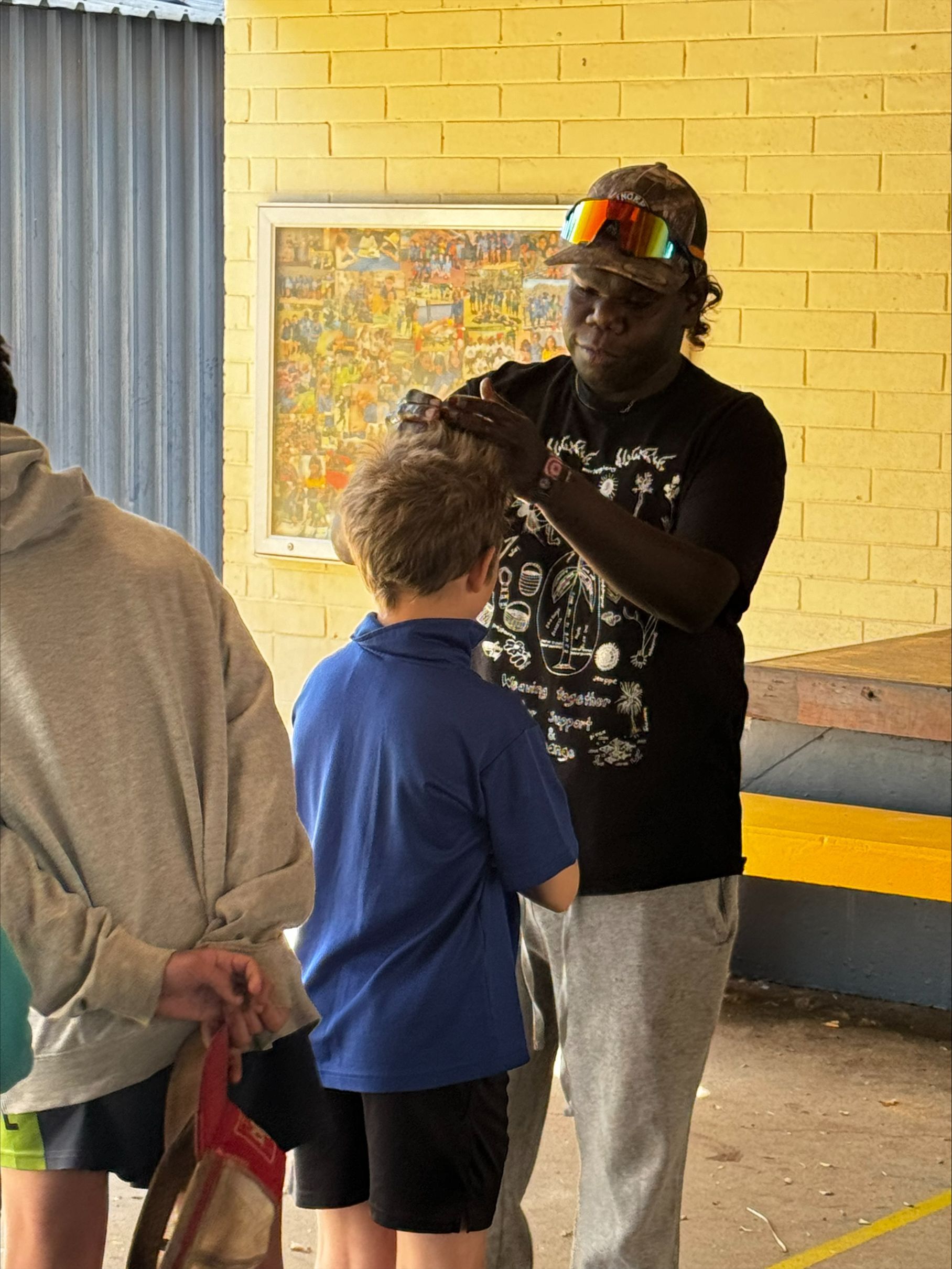 A man in a black shirt is standing next to a boy in a blue shirt.
