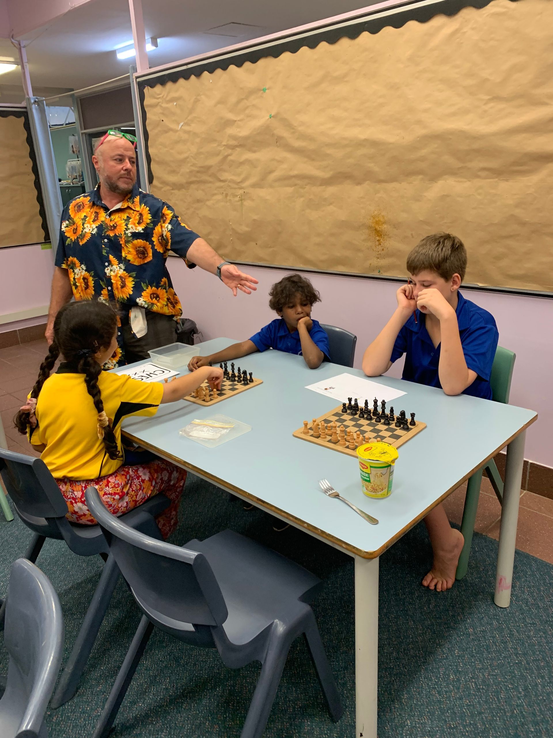 A group of children are sitting at a table playing chess