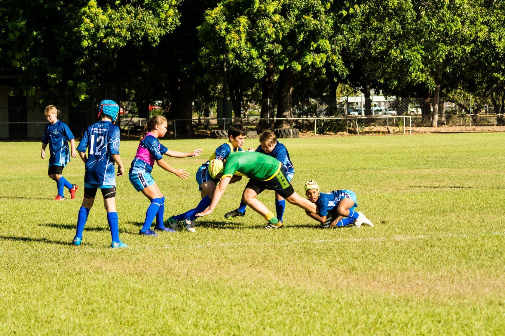 A group of children are playing rugby on a field.