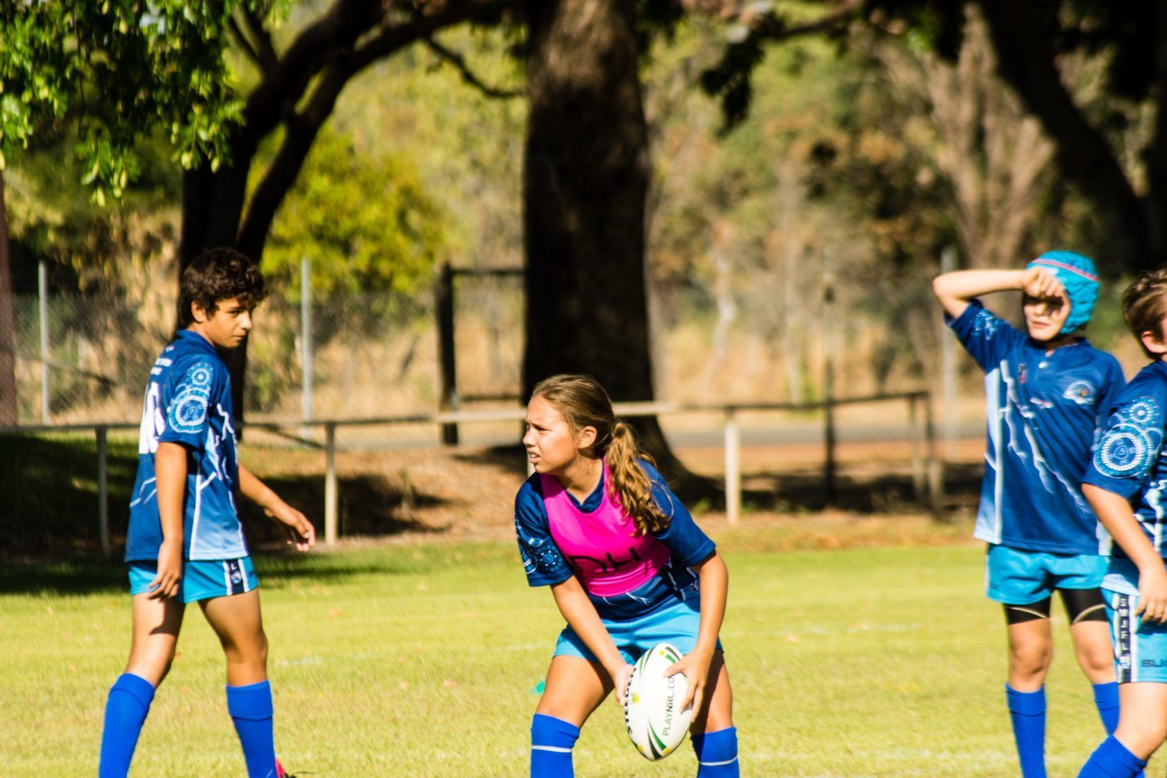 A group of young girls are playing rugby on a field.
