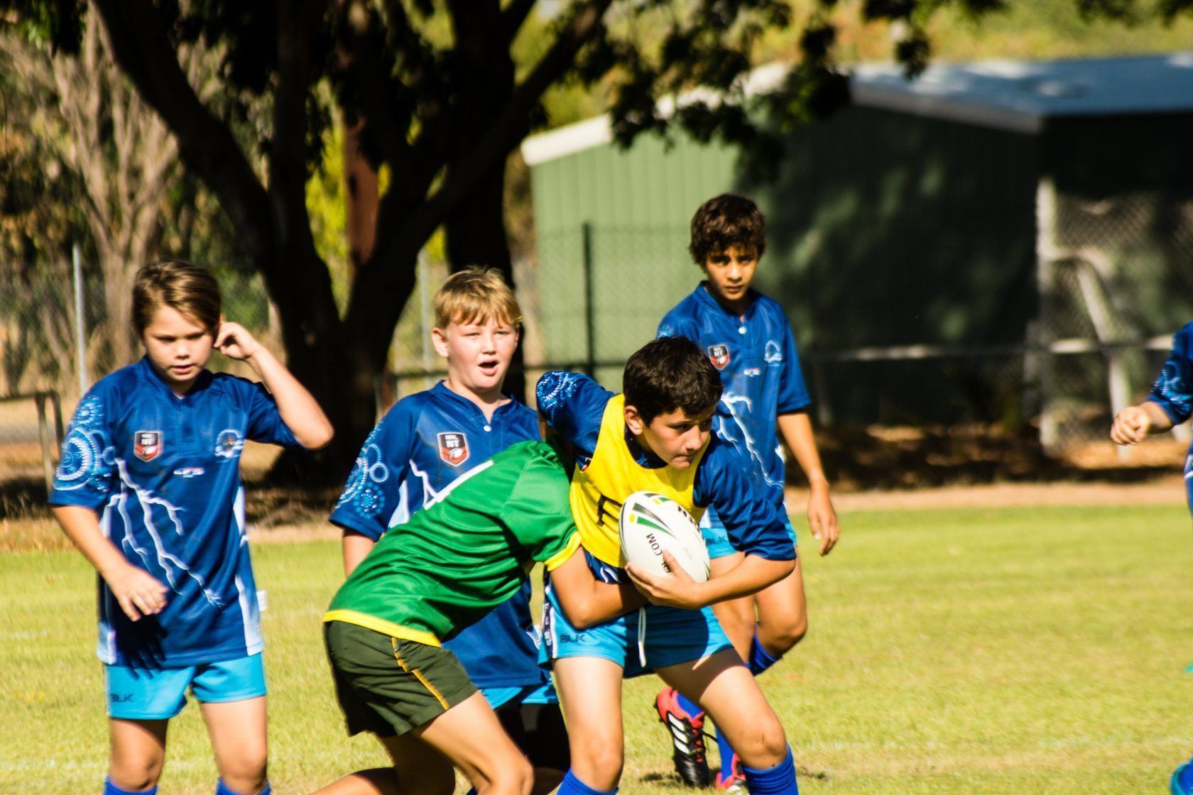 A group of young boys are playing rugby on a field.