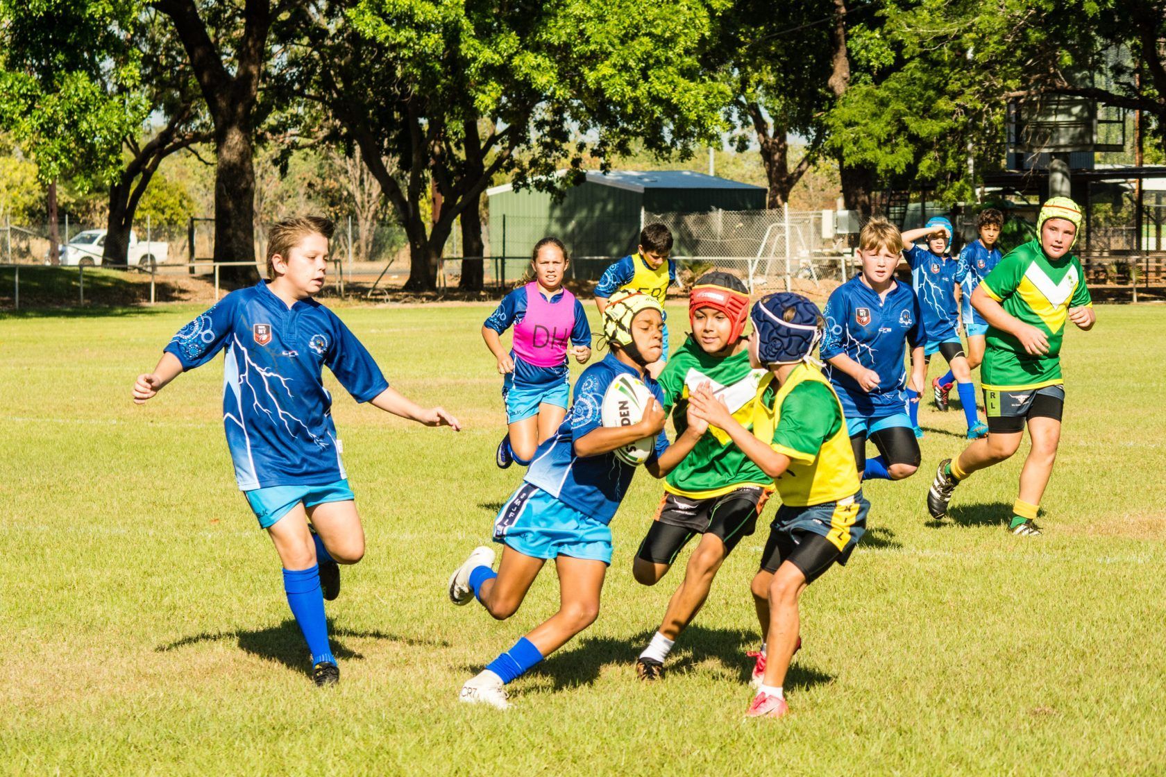A group of children are playing rugby on a field.