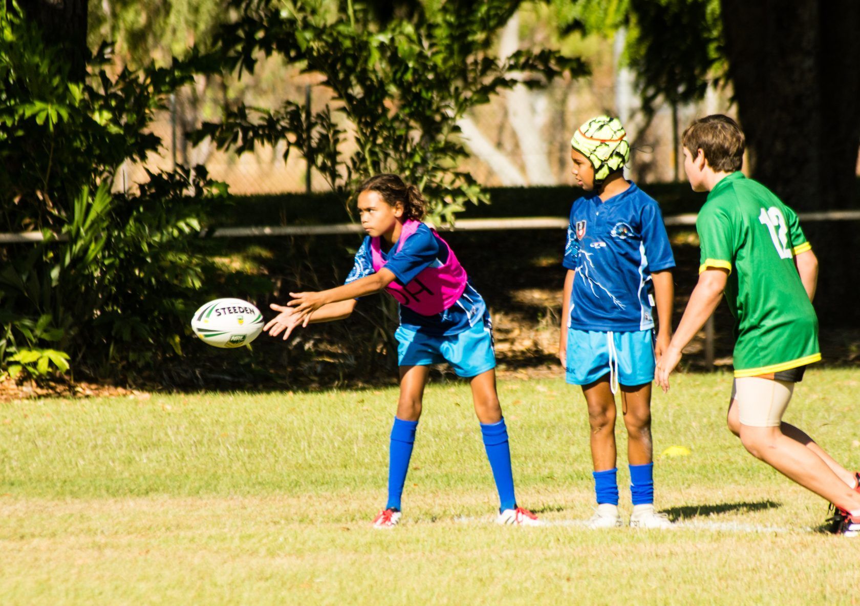 A group of children are playing rugby on a field.