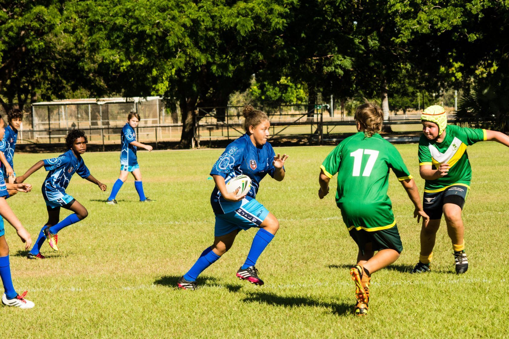 A group of young boys are playing a game of rugby on a field.