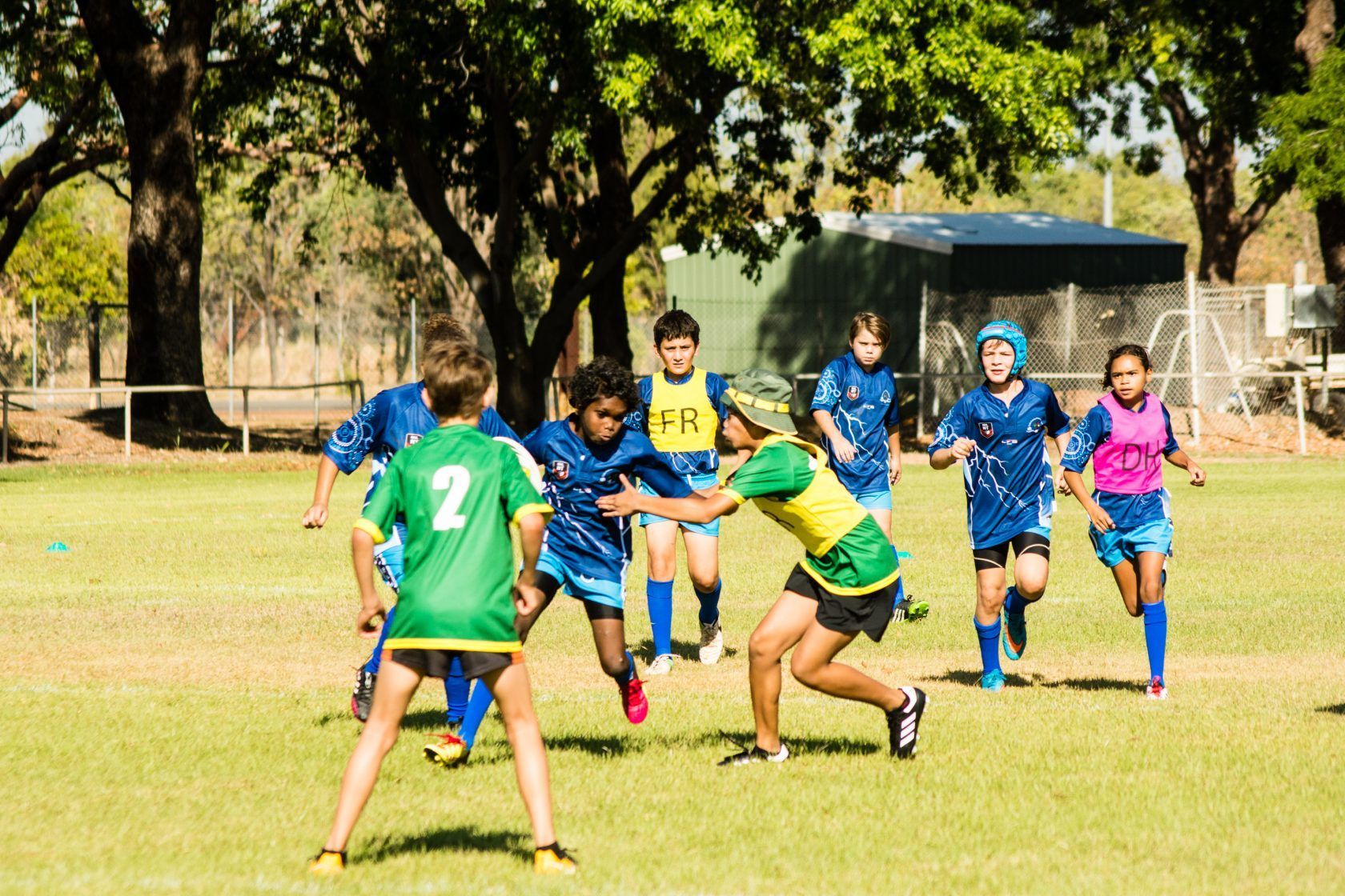 A group of young boys are playing a game of rugby on a field.