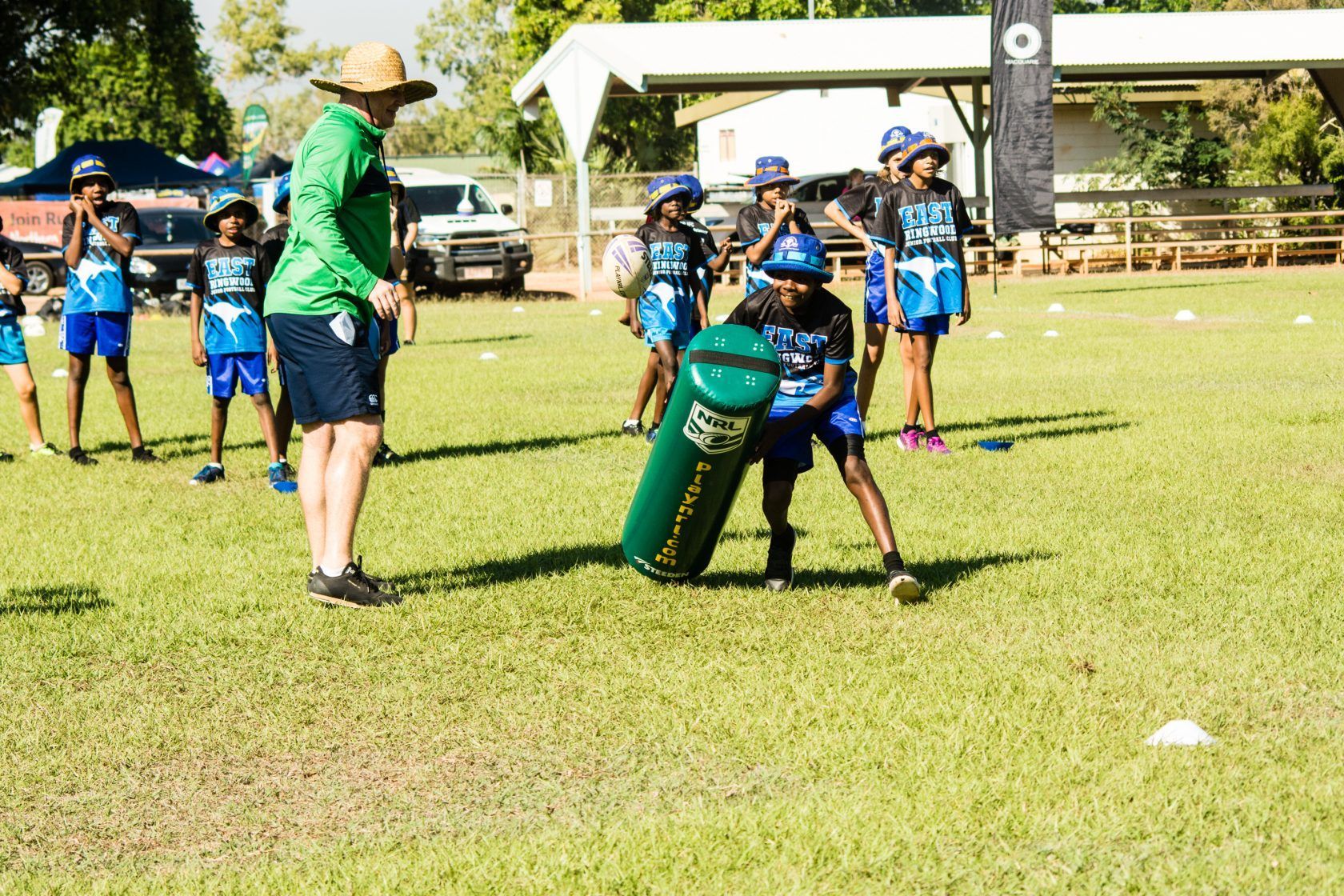 A group of children are playing a game of football on a field.