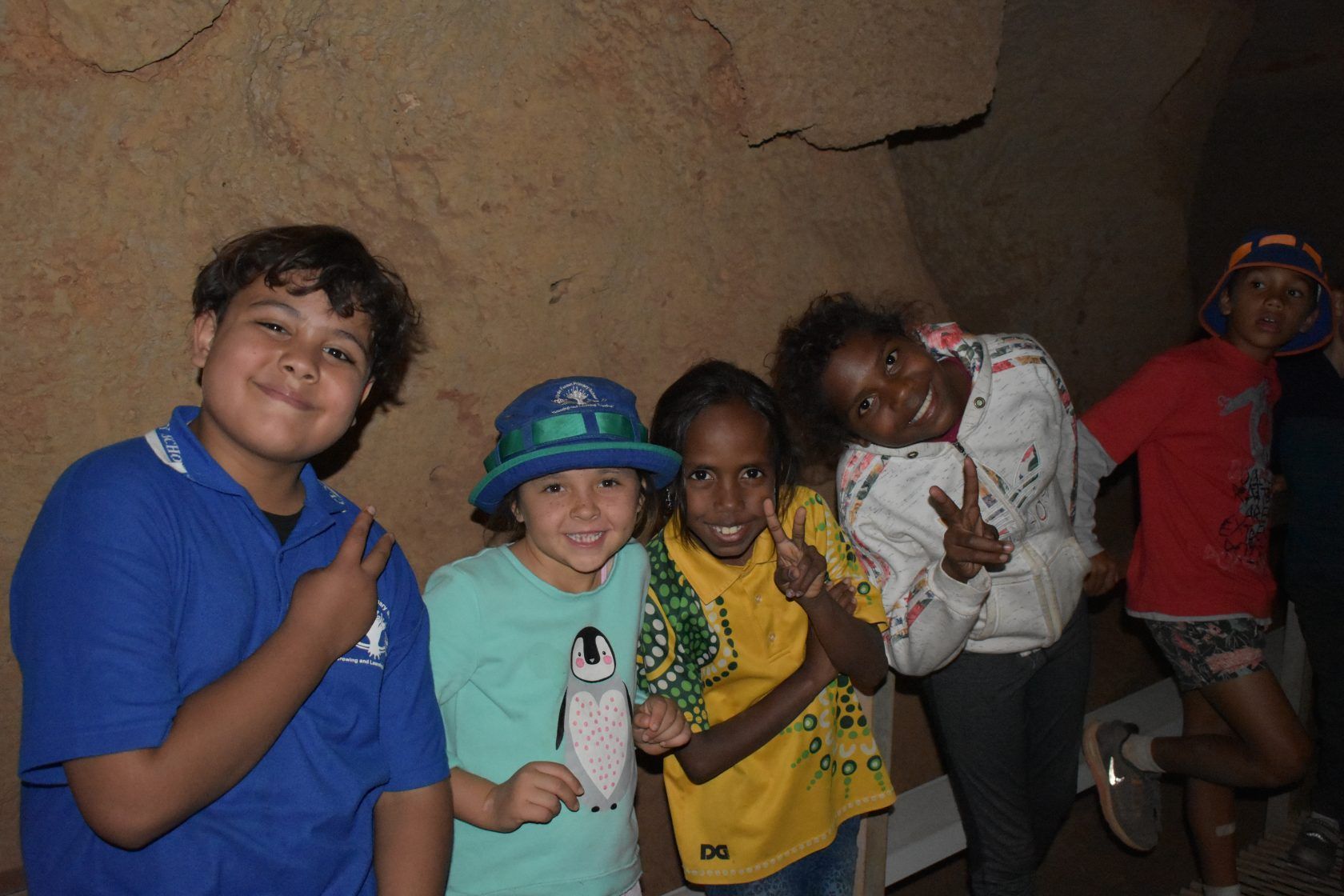 A group of children are posing for a picture and one of them is holding a stuffed penguin.