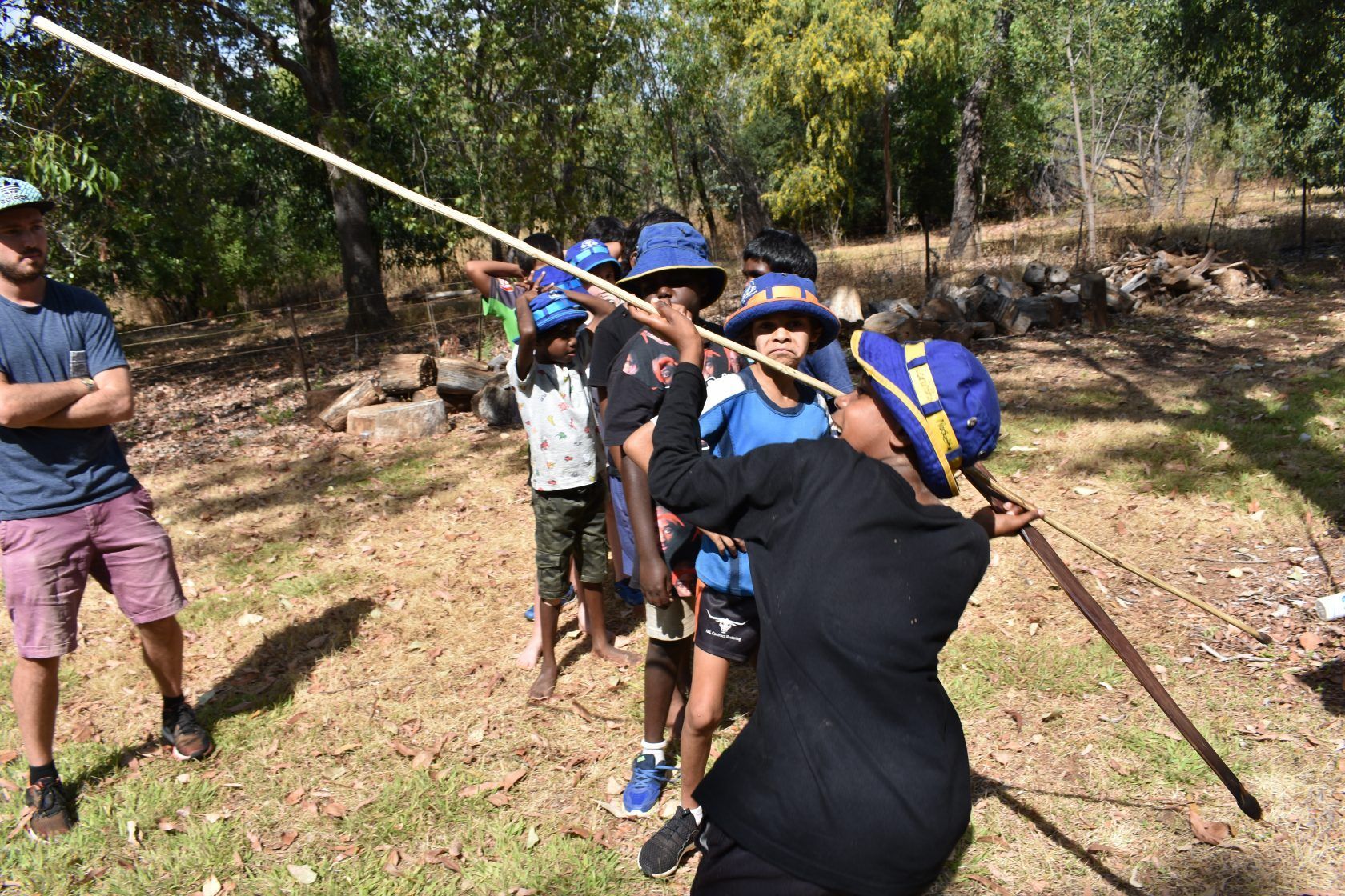 A group of people are standing in a field holding sticks.