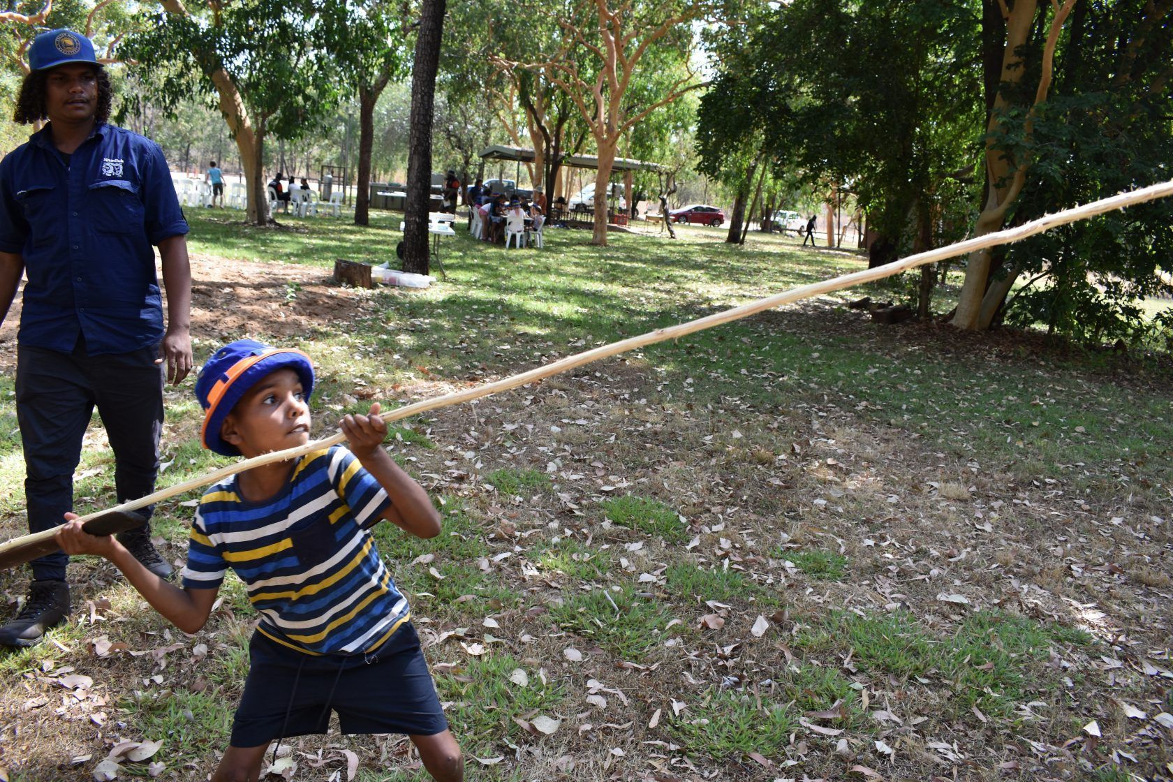 A young boy is holding a long rope in a park.