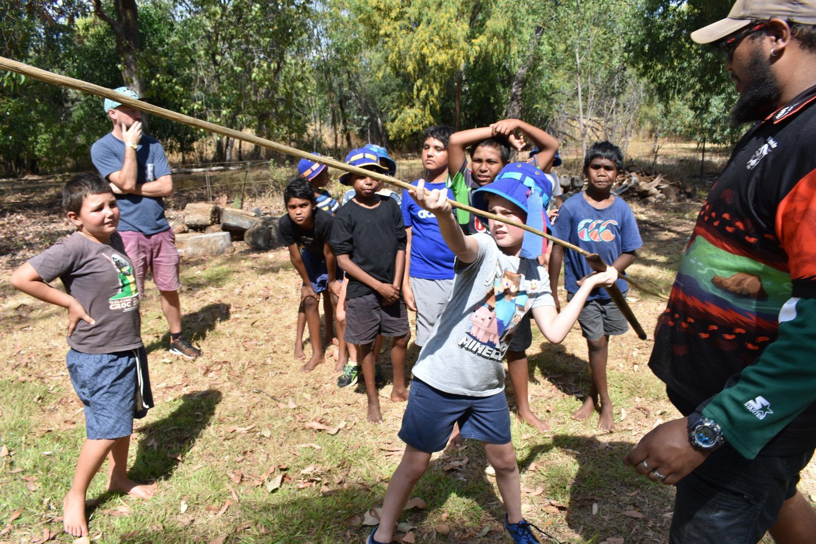 A group of students outside, one holding a large stick