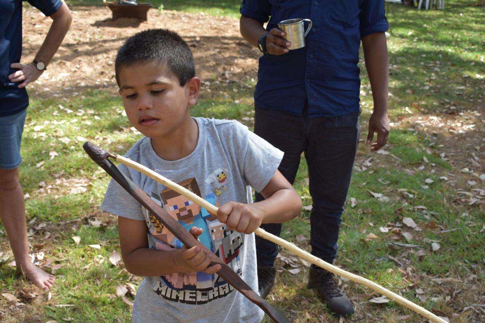 A young boy is holding a wooden stick in a park.