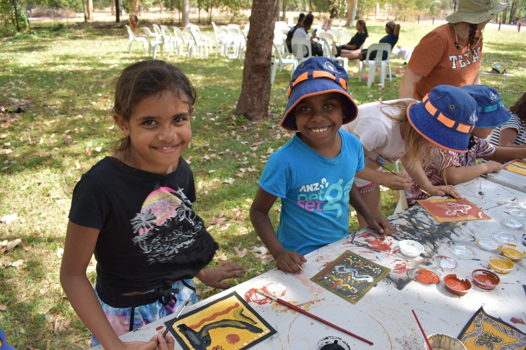A group of young girls are sitting at a table painting
