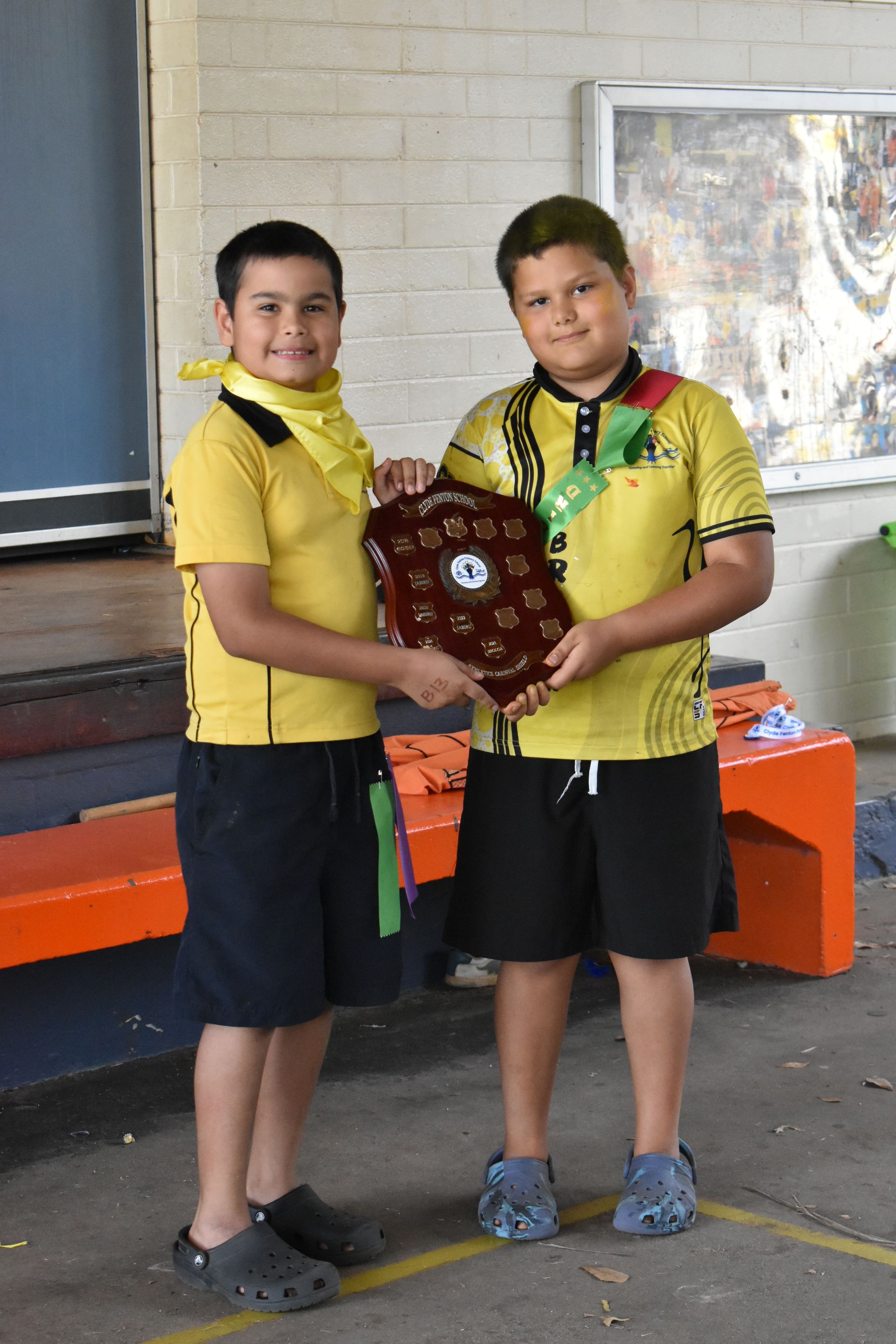 Two young boys are standing next to each other holding a plaque.
