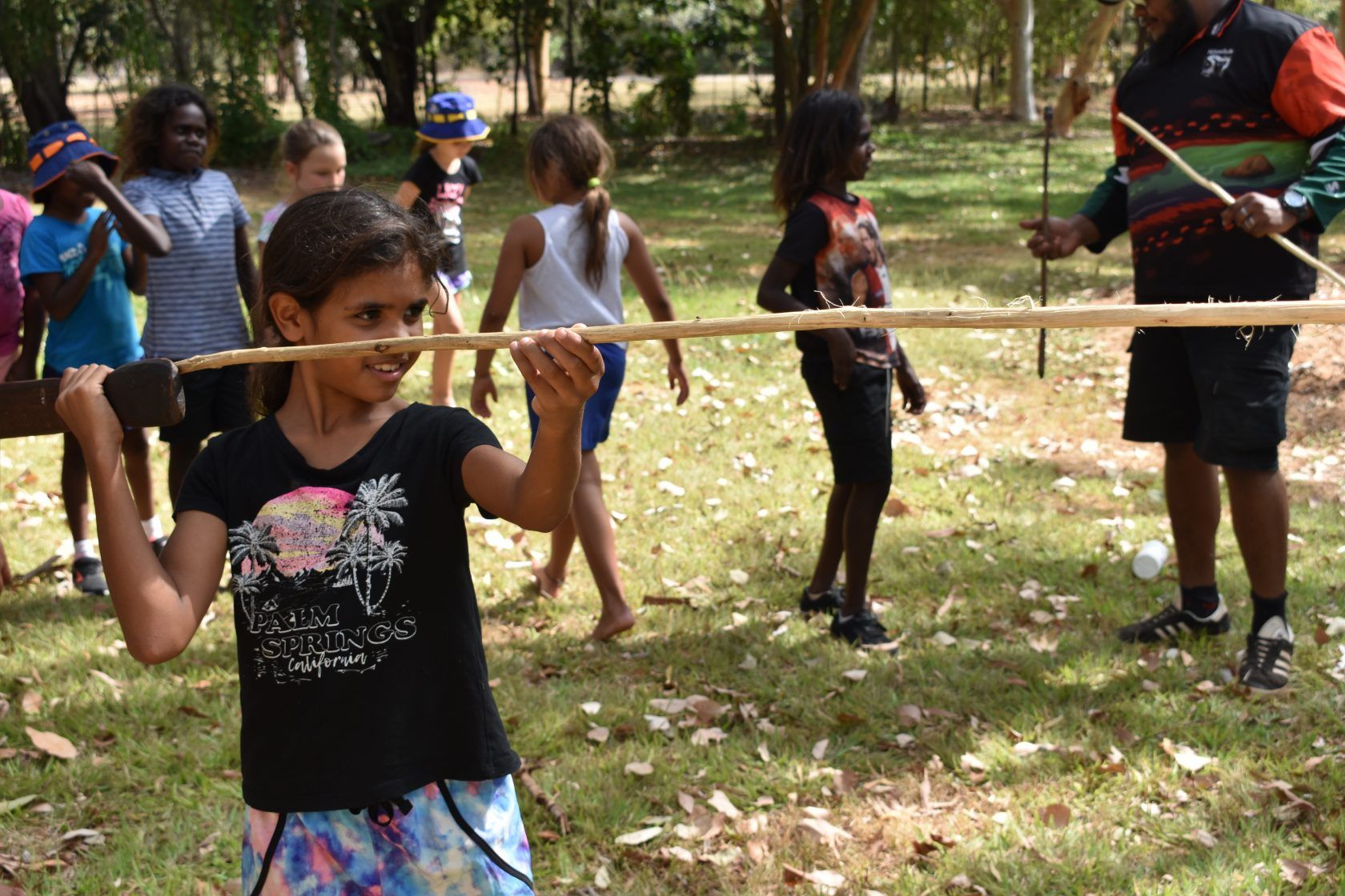 A group of children are playing with sticks in a park.