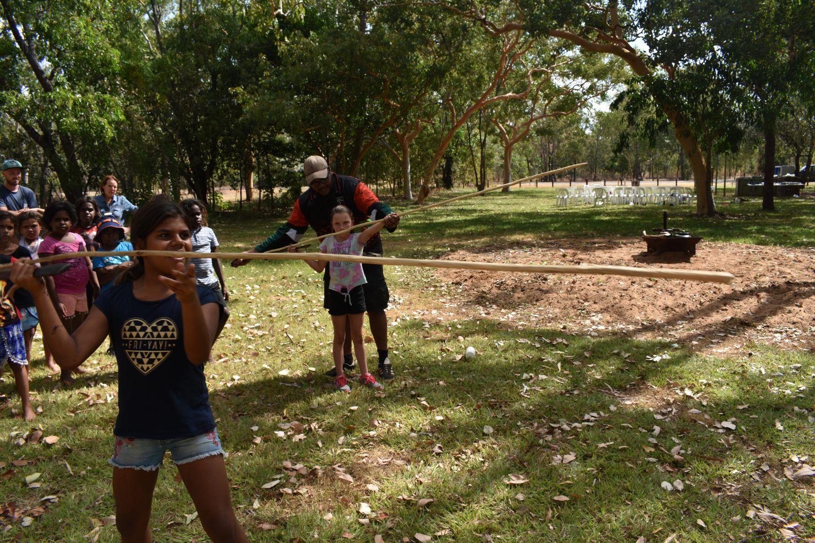 A group of children are playing with a stick in a park.