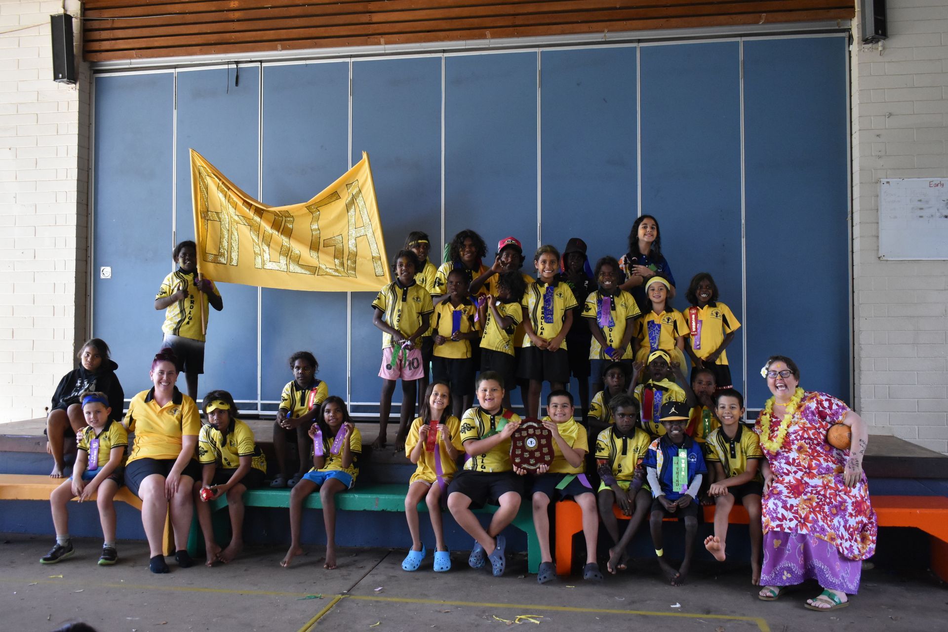 A group of children are posing for a picture in front of a blue wall.