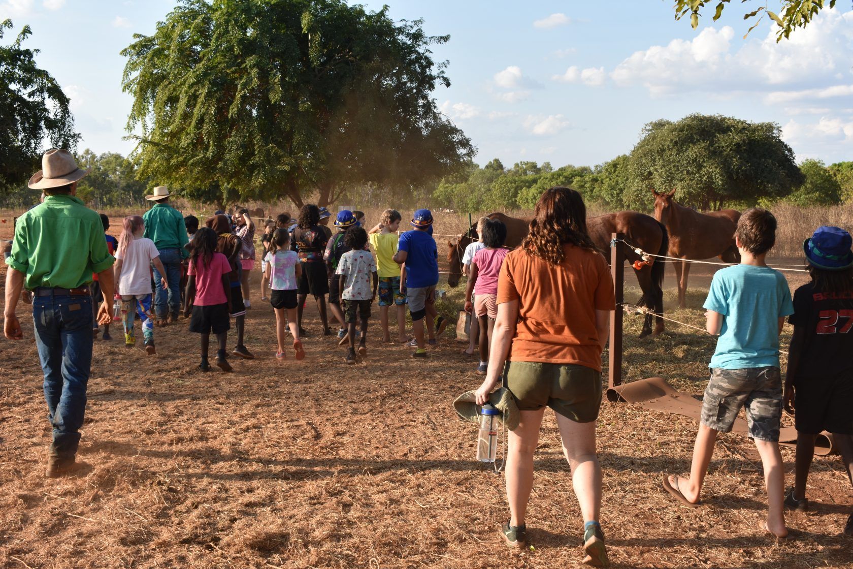 A group of people are walking in a dirt field.