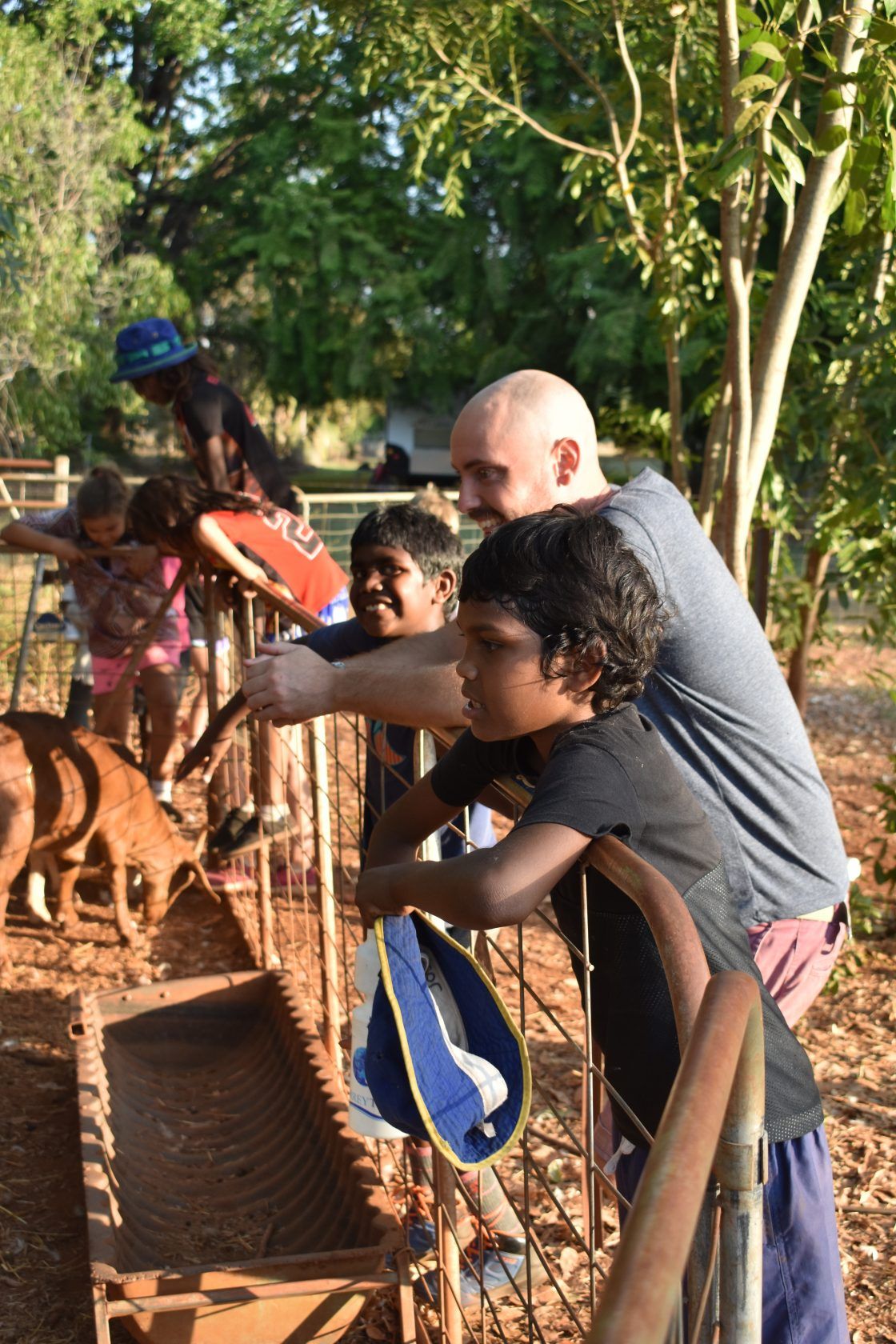A man is standing next to a boy in a fenced in area.