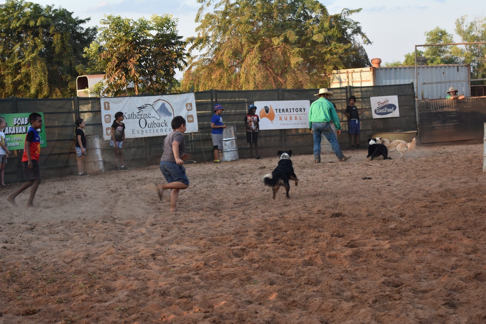 A group of people are playing soccer in a dirt field