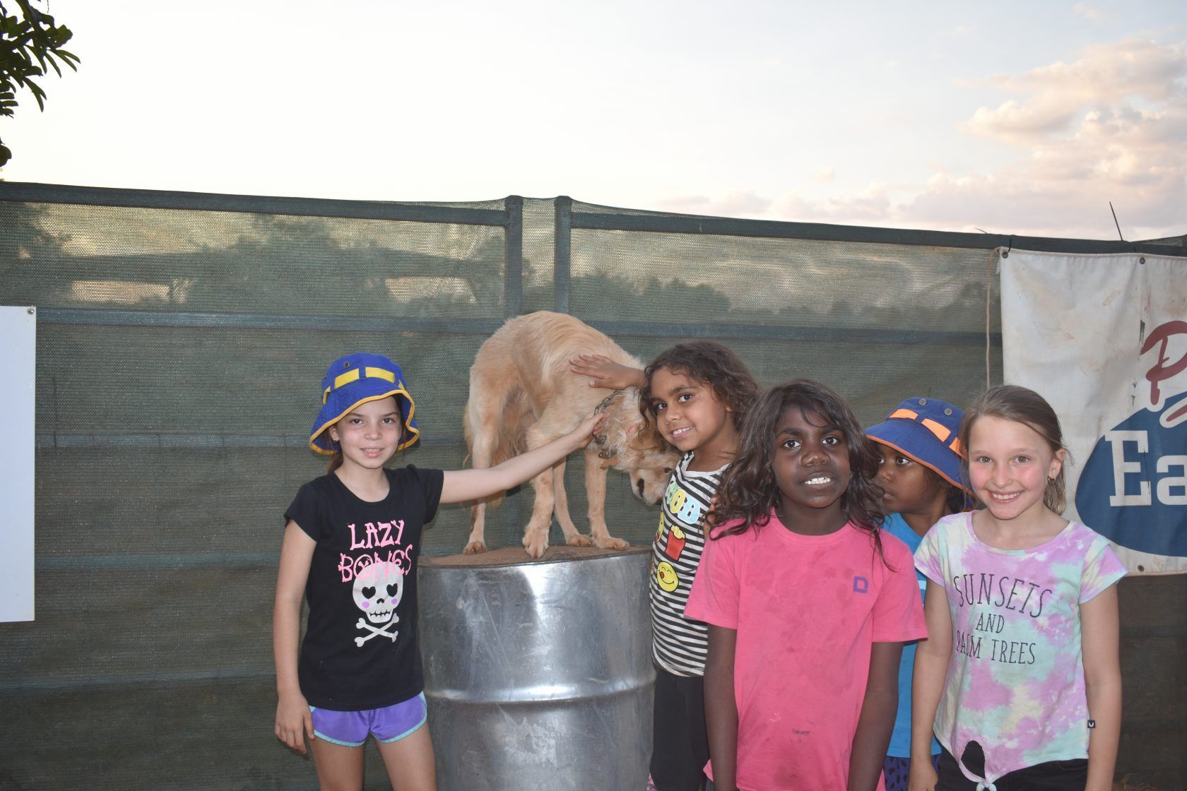 A group of young girls are posing for a picture with a dog on a barrel.