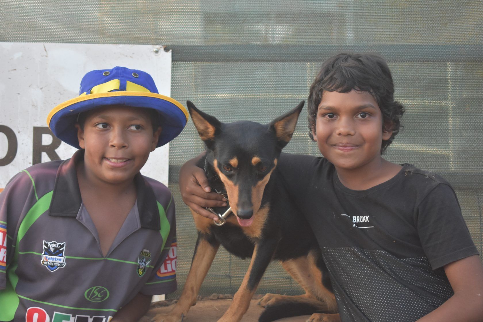 Two young boys are posing for a picture with a dog
