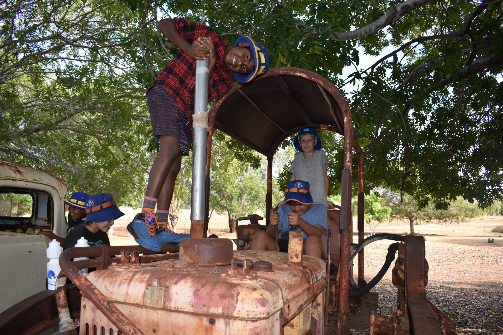 A group of children are playing on an old rusty tractor.