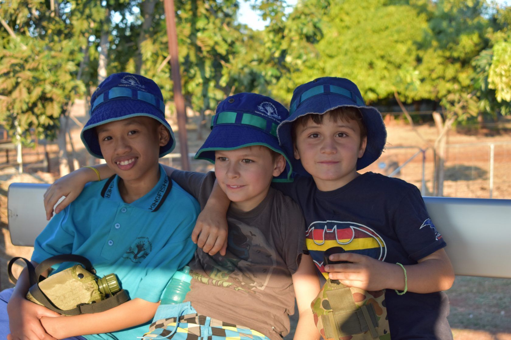 Three young boys are posing for a picture while sitting on a bench.
