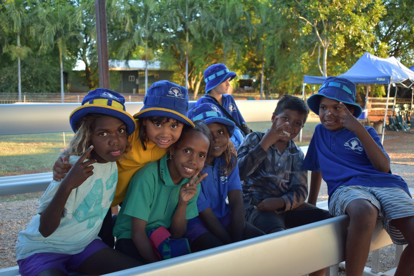 A group of children are posing for a picture while sitting on a bench.