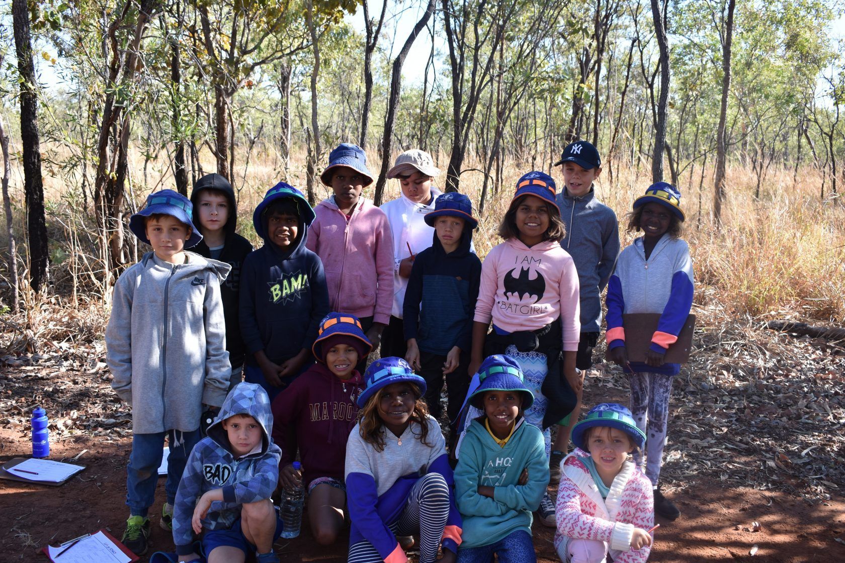 A group of children are posing for a picture in the woods.