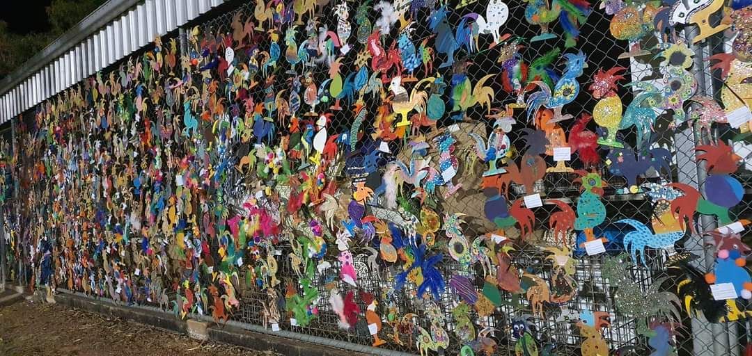 A fence with a lot of colorful stickers on it.