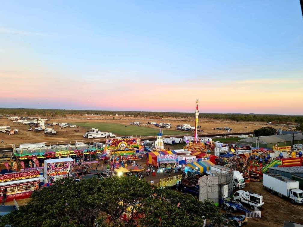 An aerial view of a carnival with a ferris wheel in the foreground.