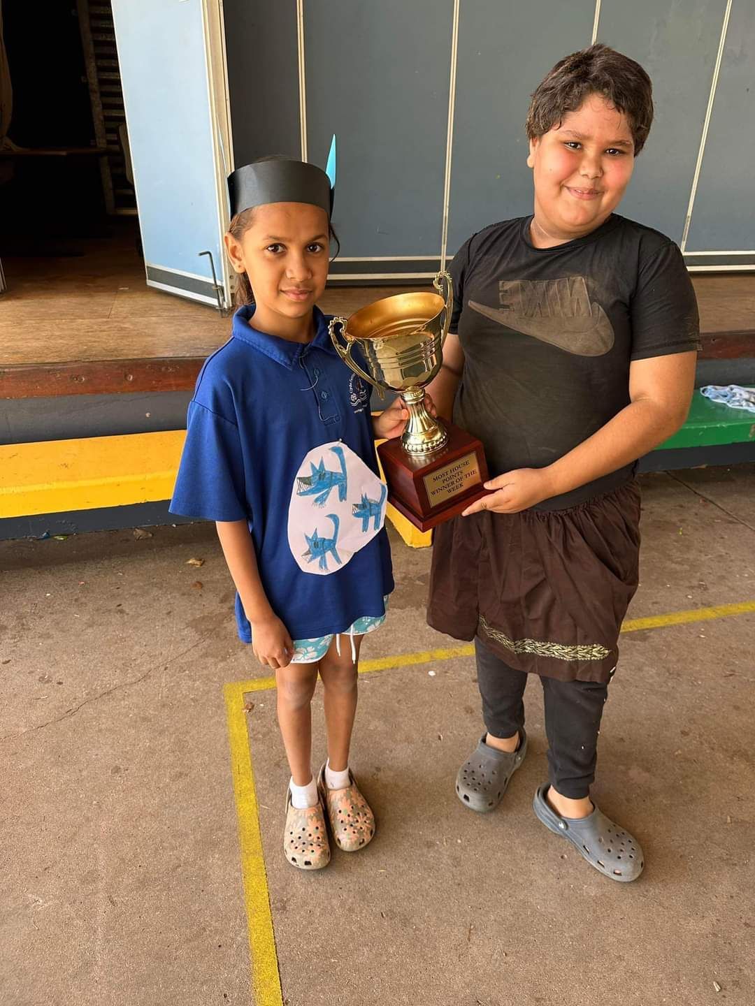 A boy and a girl are standing next to each other holding a trophy.