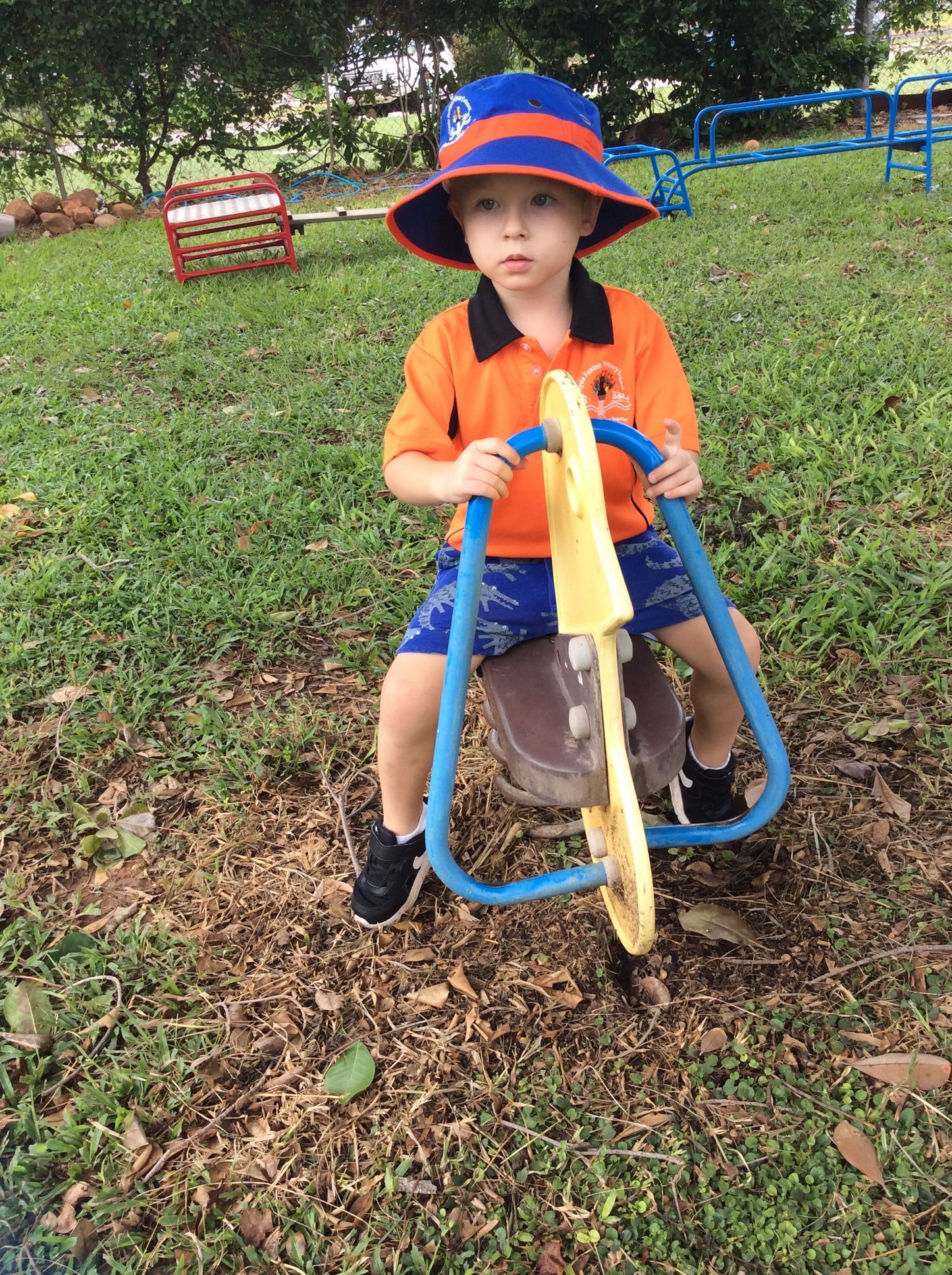 A young boy is riding a rocking horse in a park.