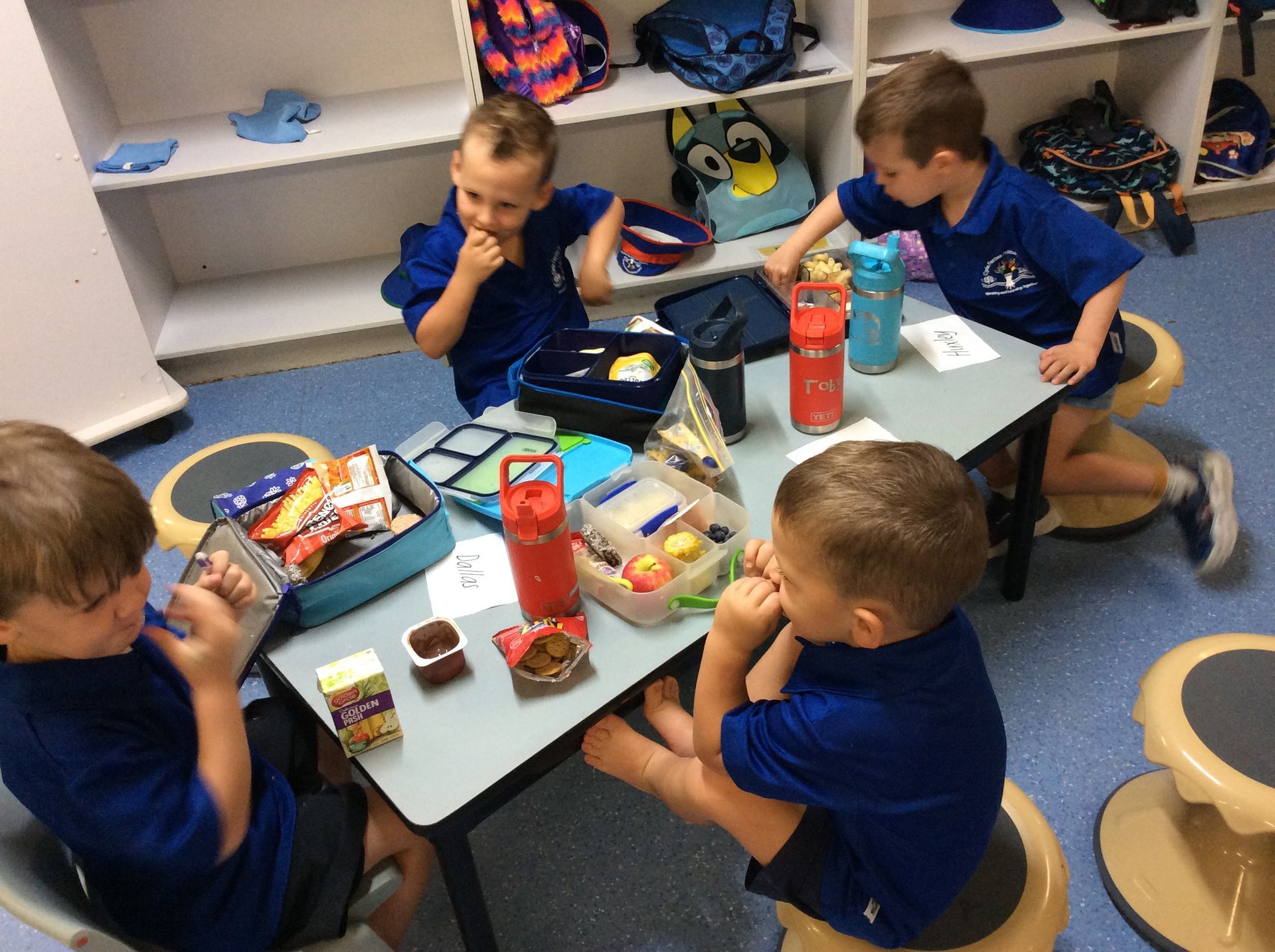 A group of young boys are sitting at a table eating snacks.