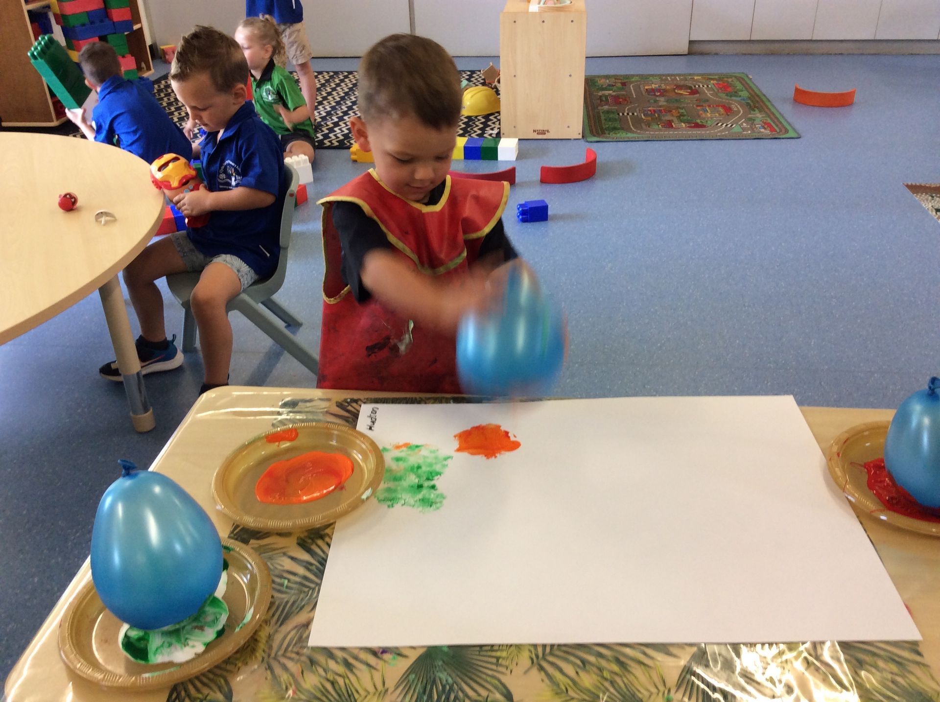 A young boy is playing with water balloons on a table.