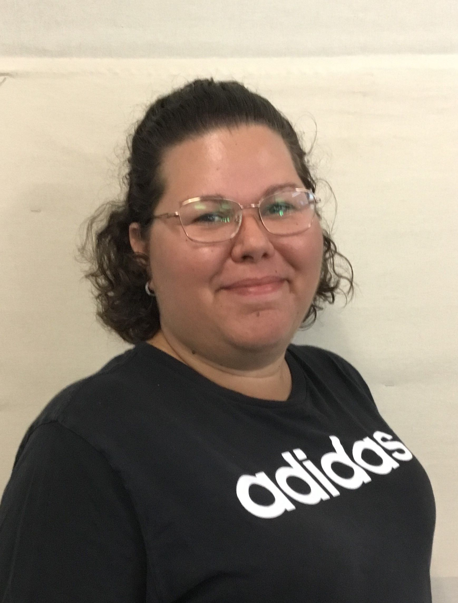 A woman wearing glasses and a black adidas shirt