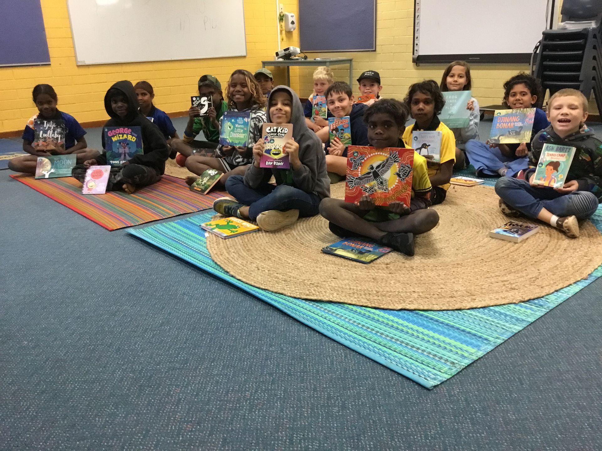 A group of children are sitting on the floor holding books.