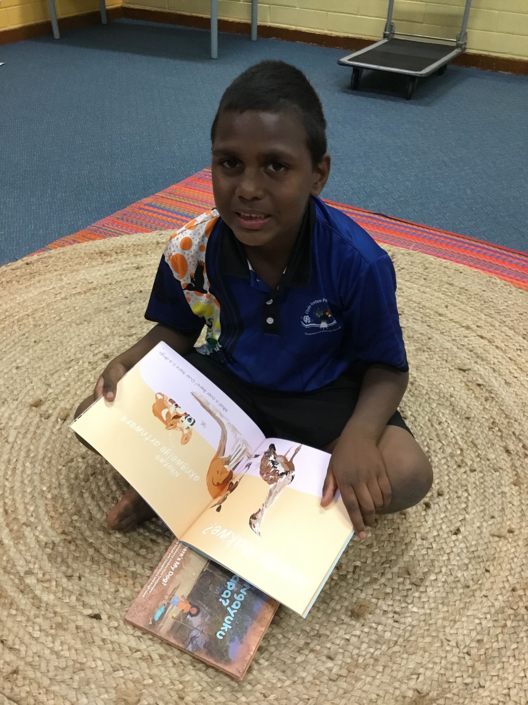 A young boy is sitting on the floor reading a book.