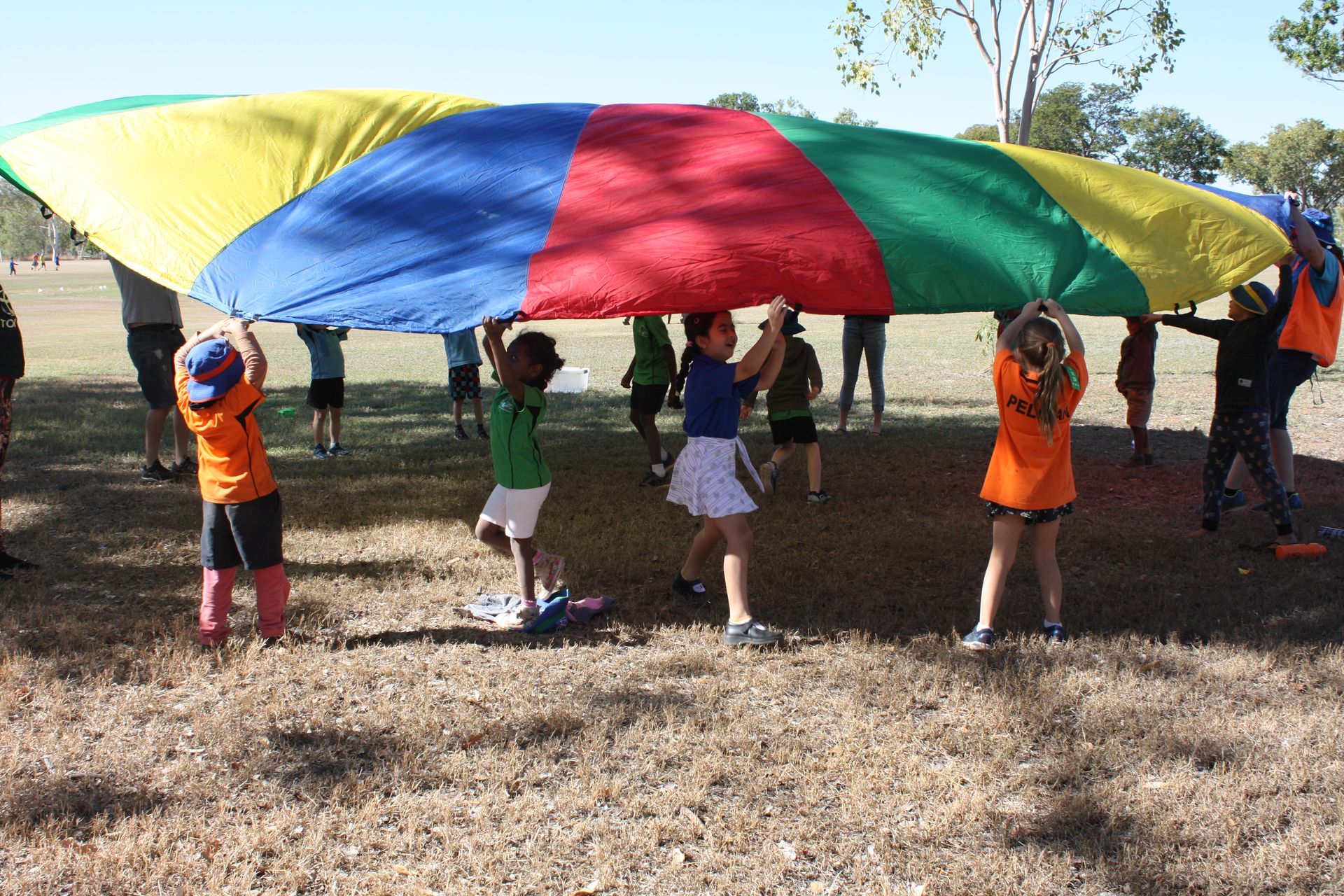 A group of children holding a colorful parachute in a field