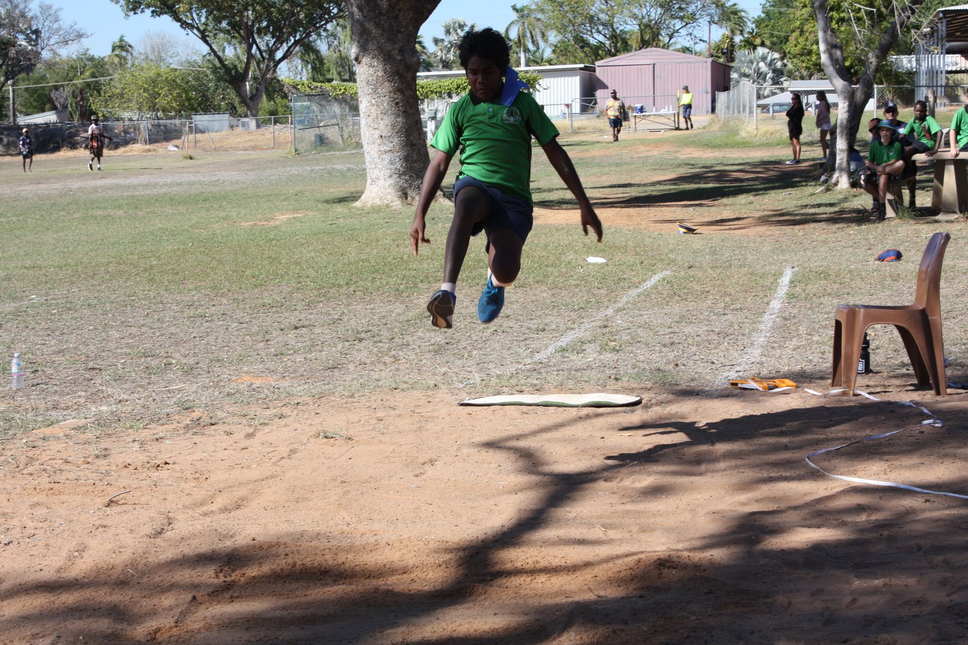 A boy in a green shirt is jumping in the air