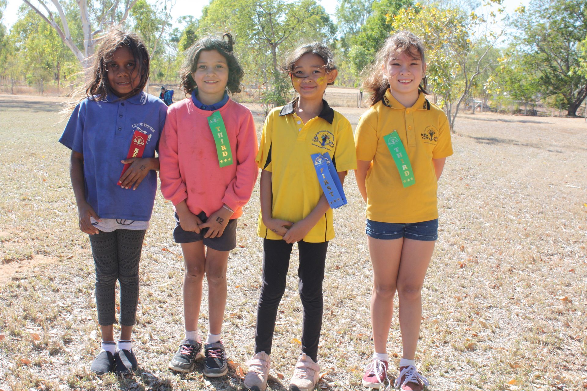 Four young girls are posing for a picture in a field.
