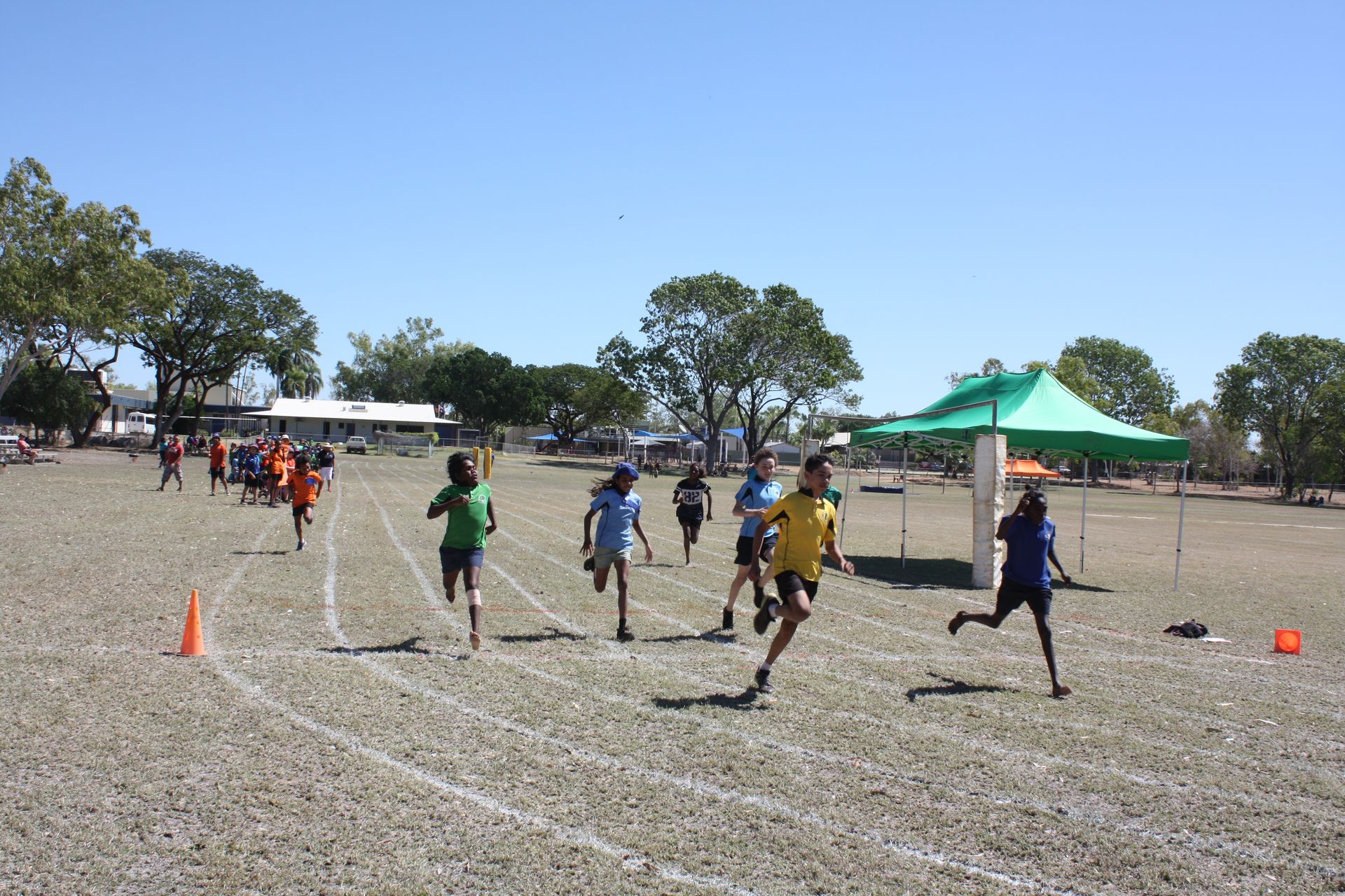A group of children are running on a track in a field